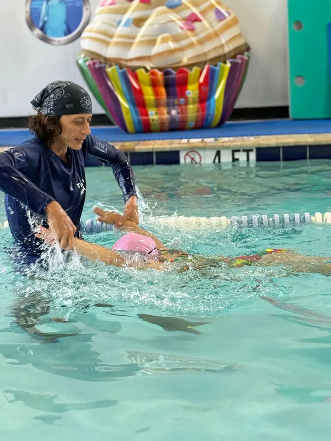 An instructor correcting a swimmer’s freestyle arm recovery mid-stroke