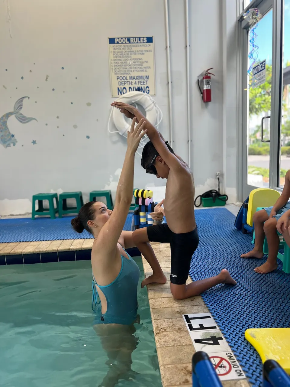 A swimmer pushing off the wall in a tight streamline, arms locked above the head